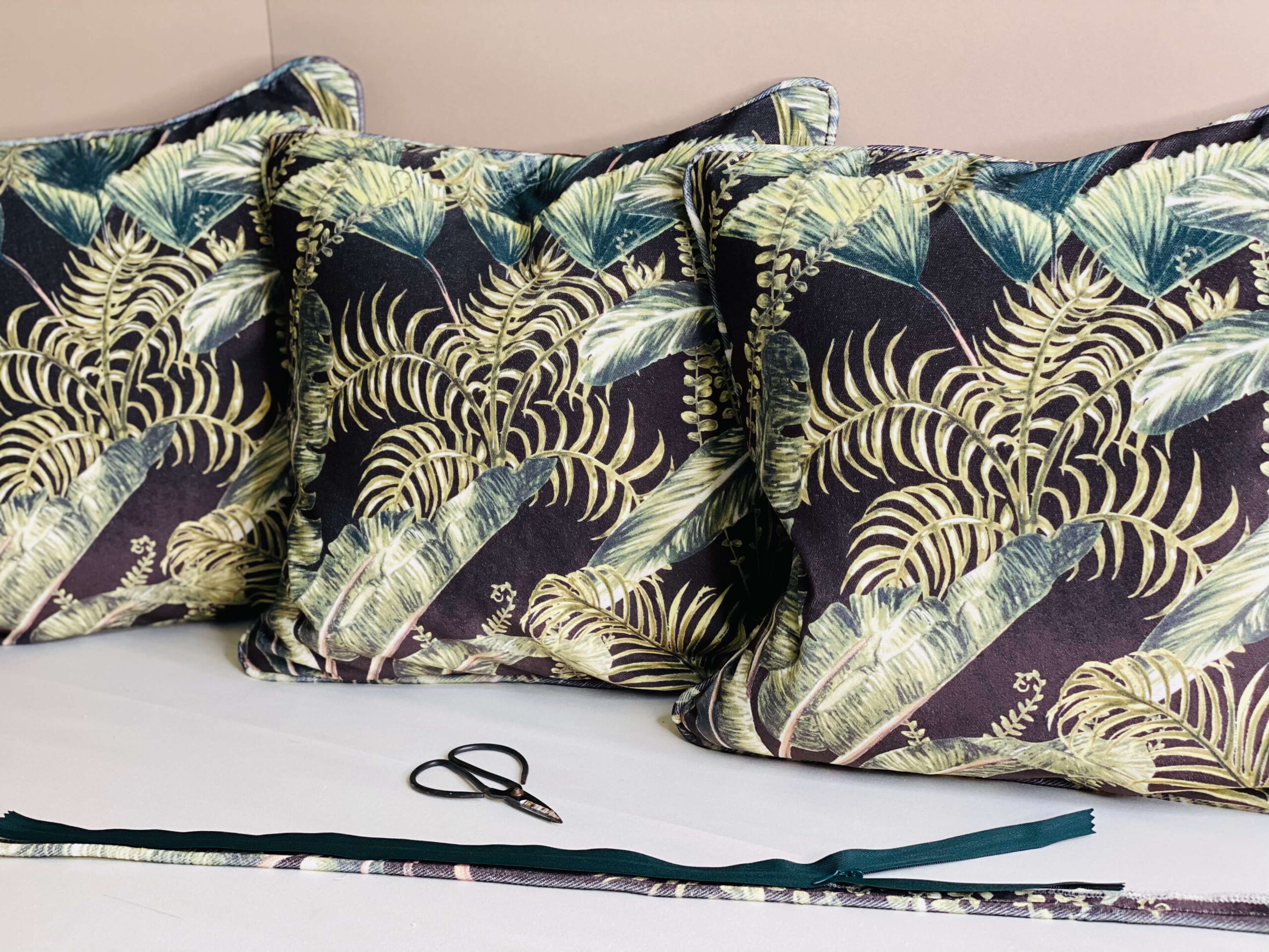 Green leafy cushions against a cream background with scissors and trim in the foreground