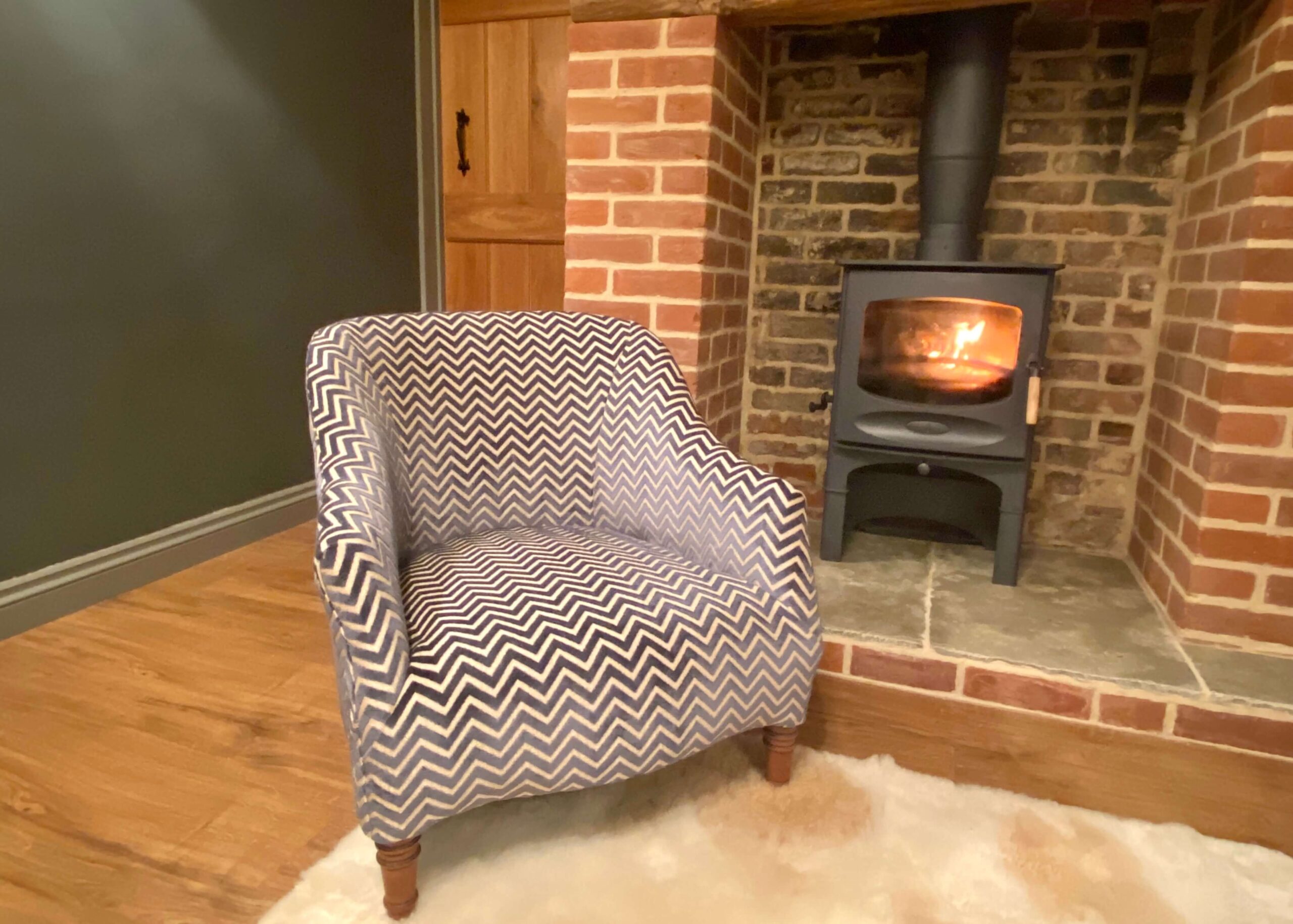 Upholstered chair in front of a fireplace and brick details