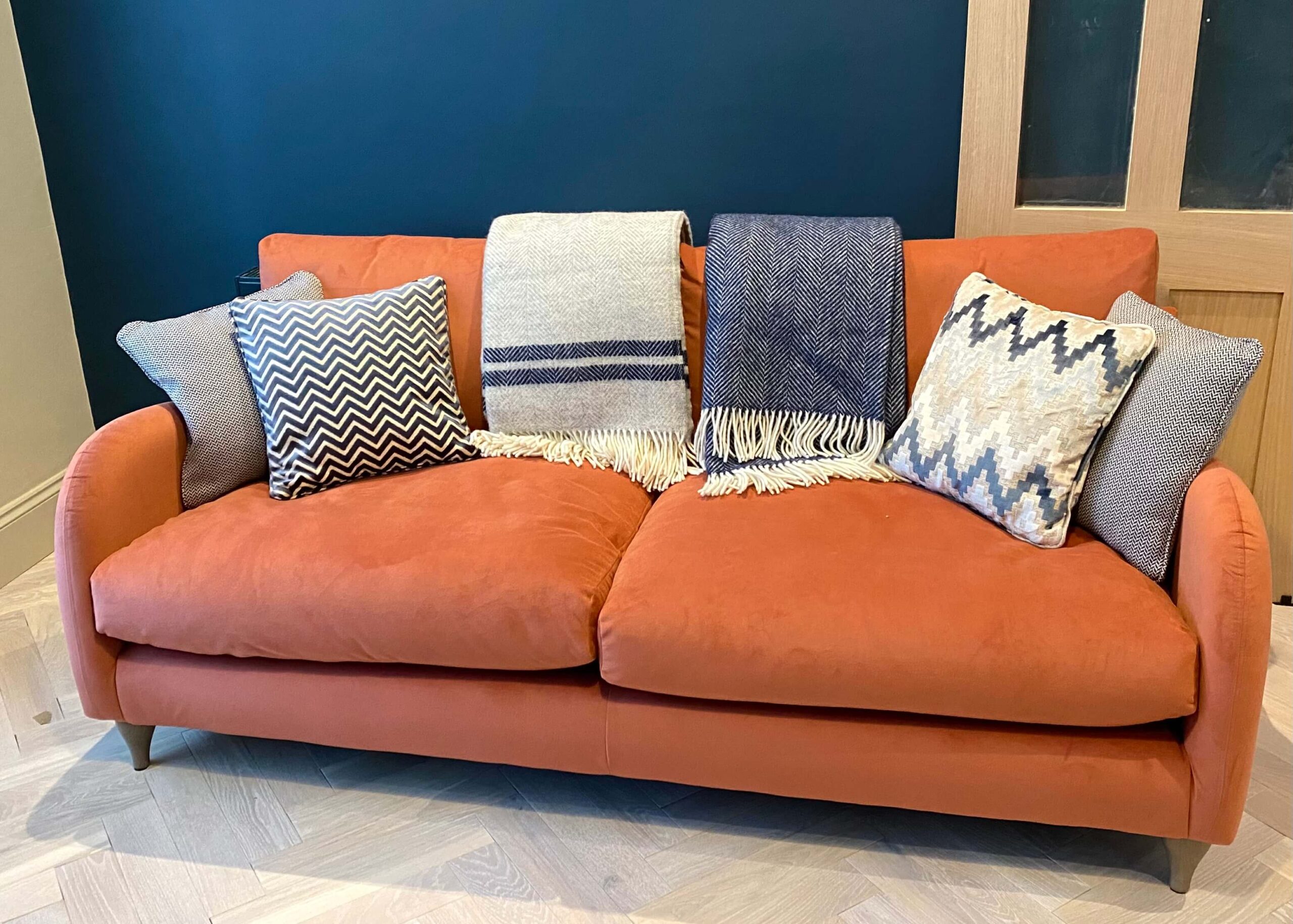 Orange sofa with blue throws and cushions against a blue wall