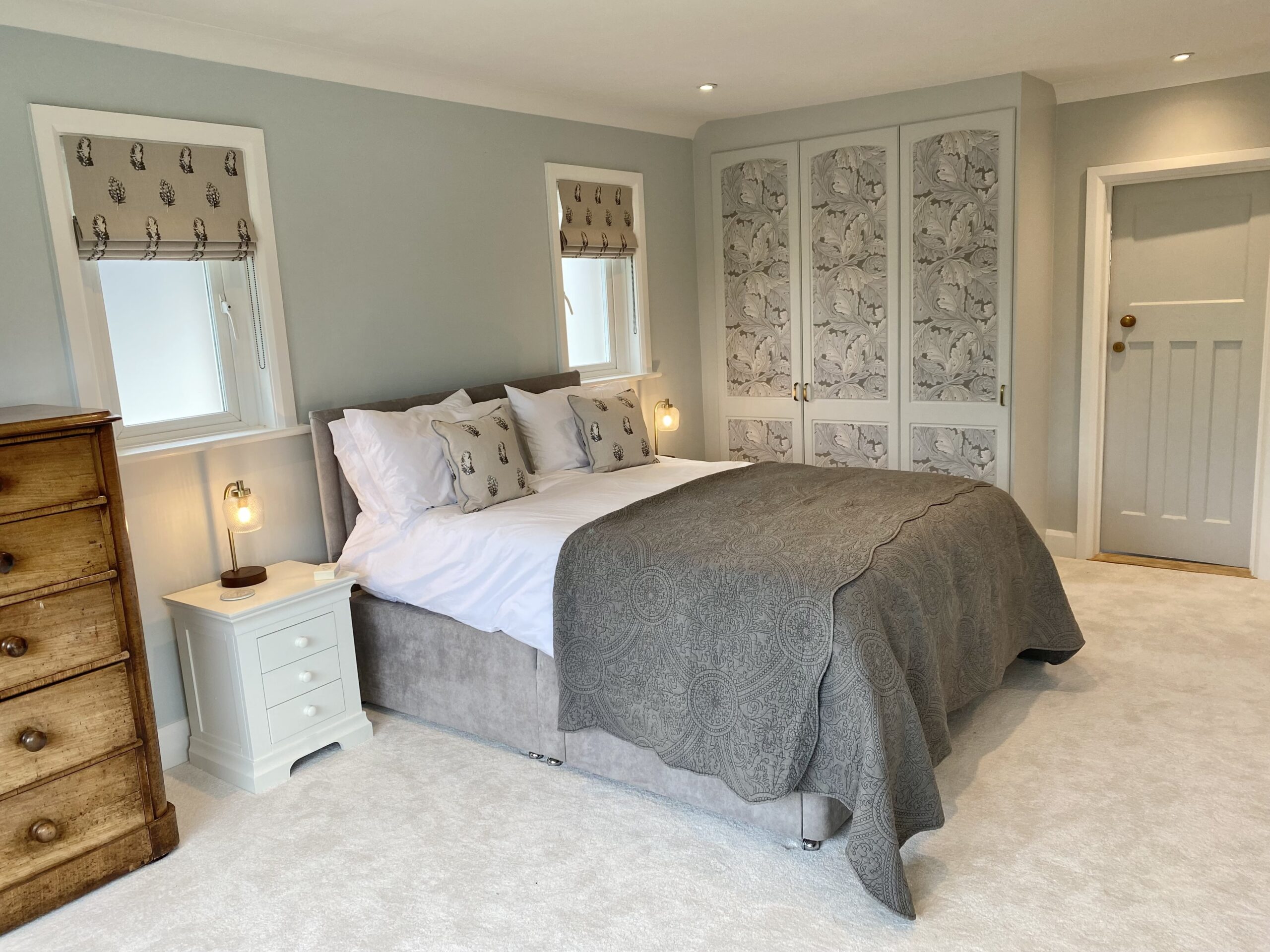 Master bedroom with neutral tones. Bed in the middle, dresser to the left. 