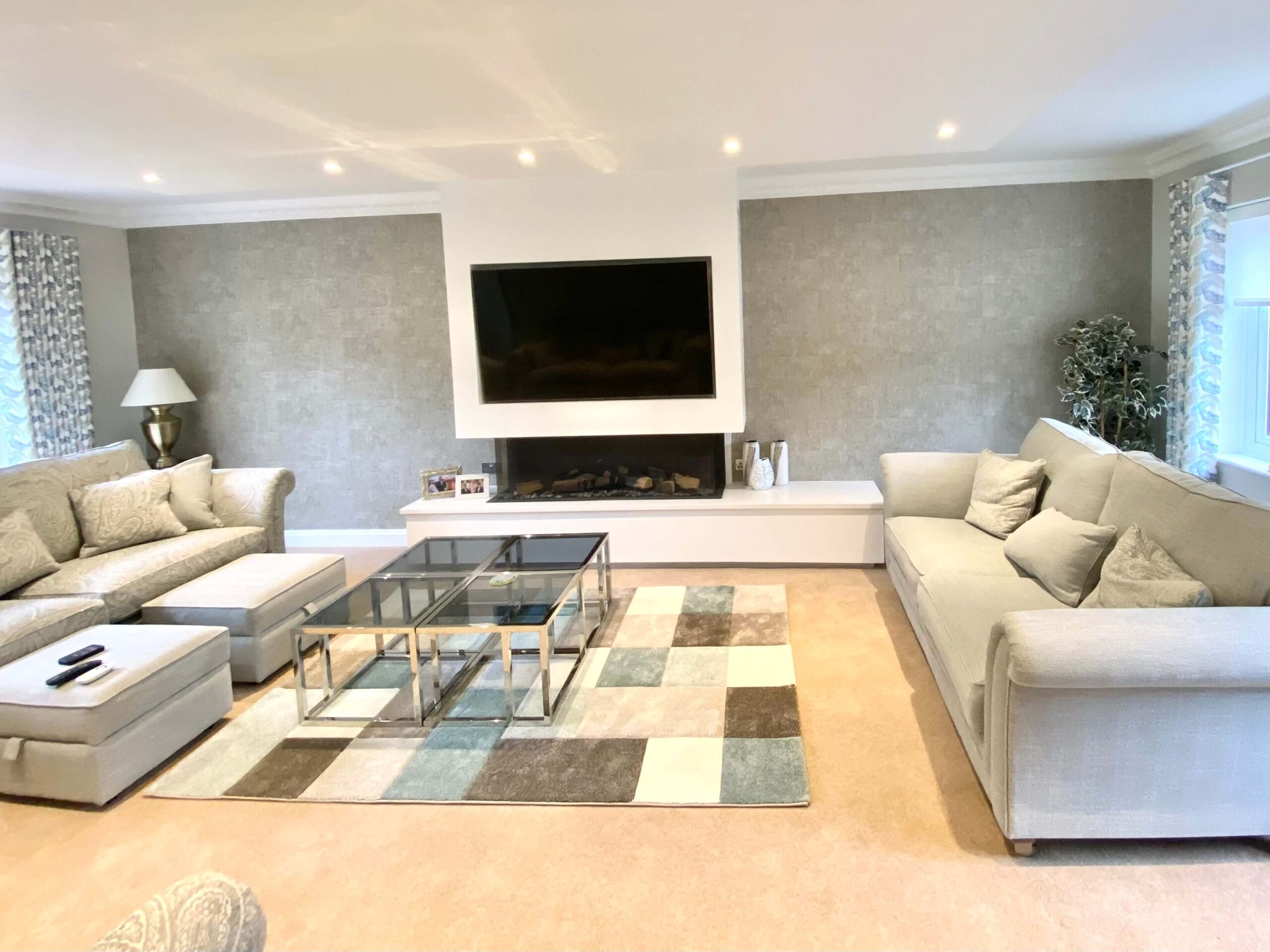 Neutral toned sitting room with glass table and ottomans 