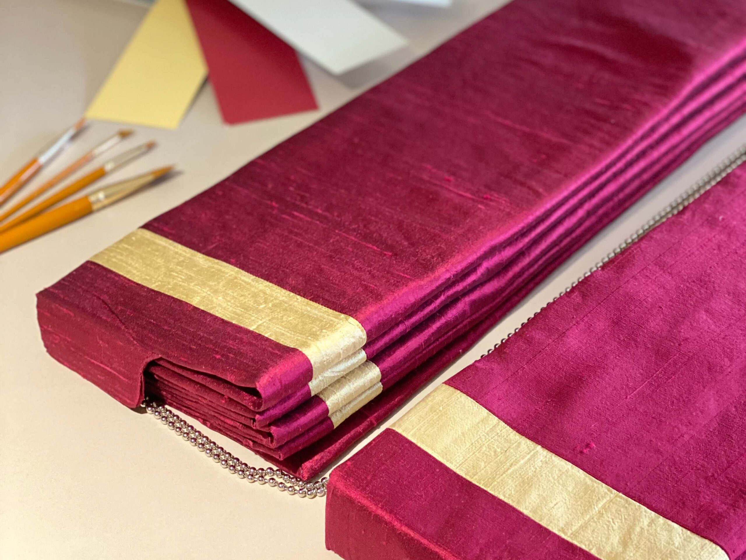 Red and gold Roman blinds on a table with colour swatches