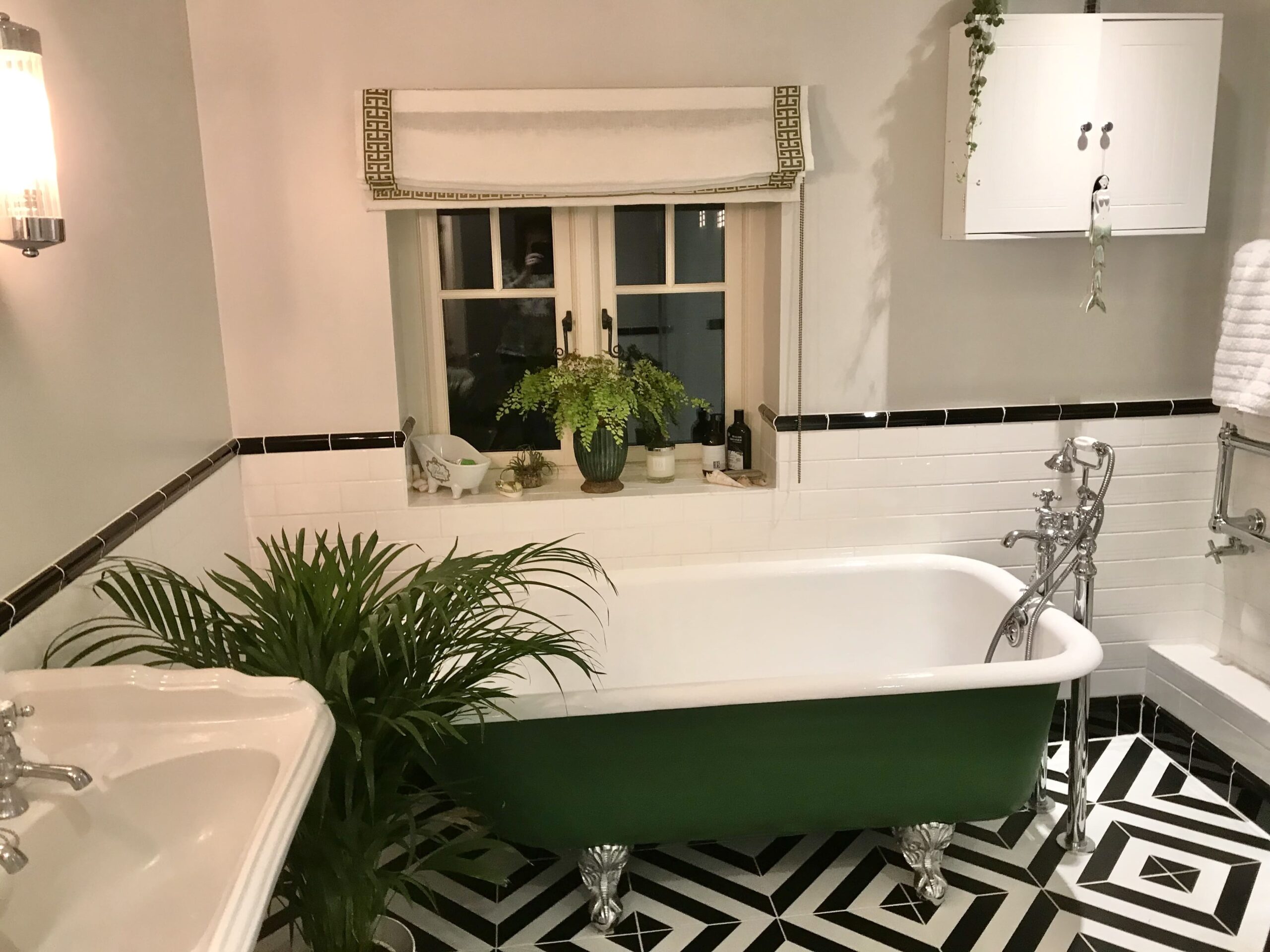 A bathroom with a tiled patterned floor a bath tub and greenery 