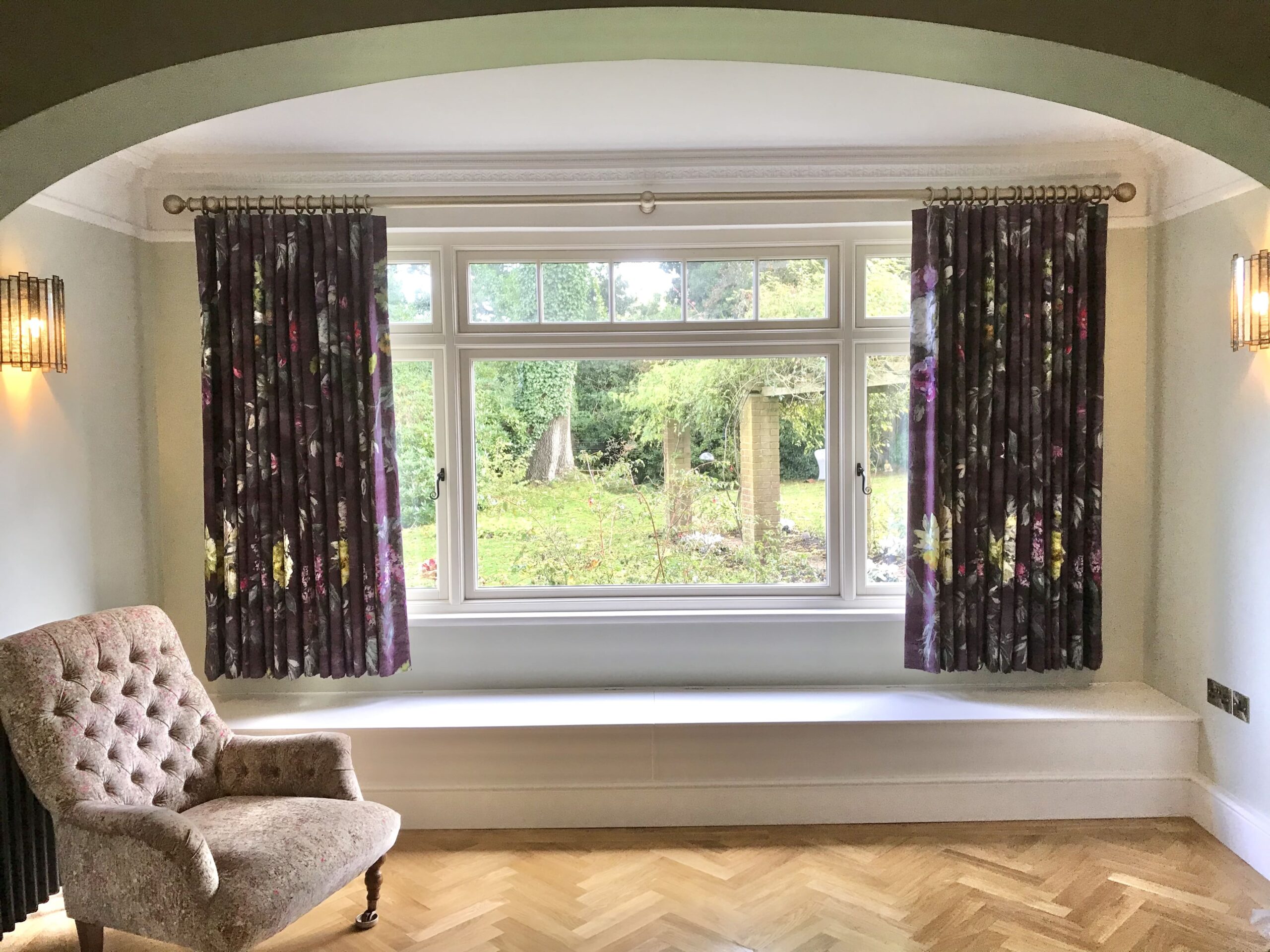 Chair in front of a window with floral curtains 