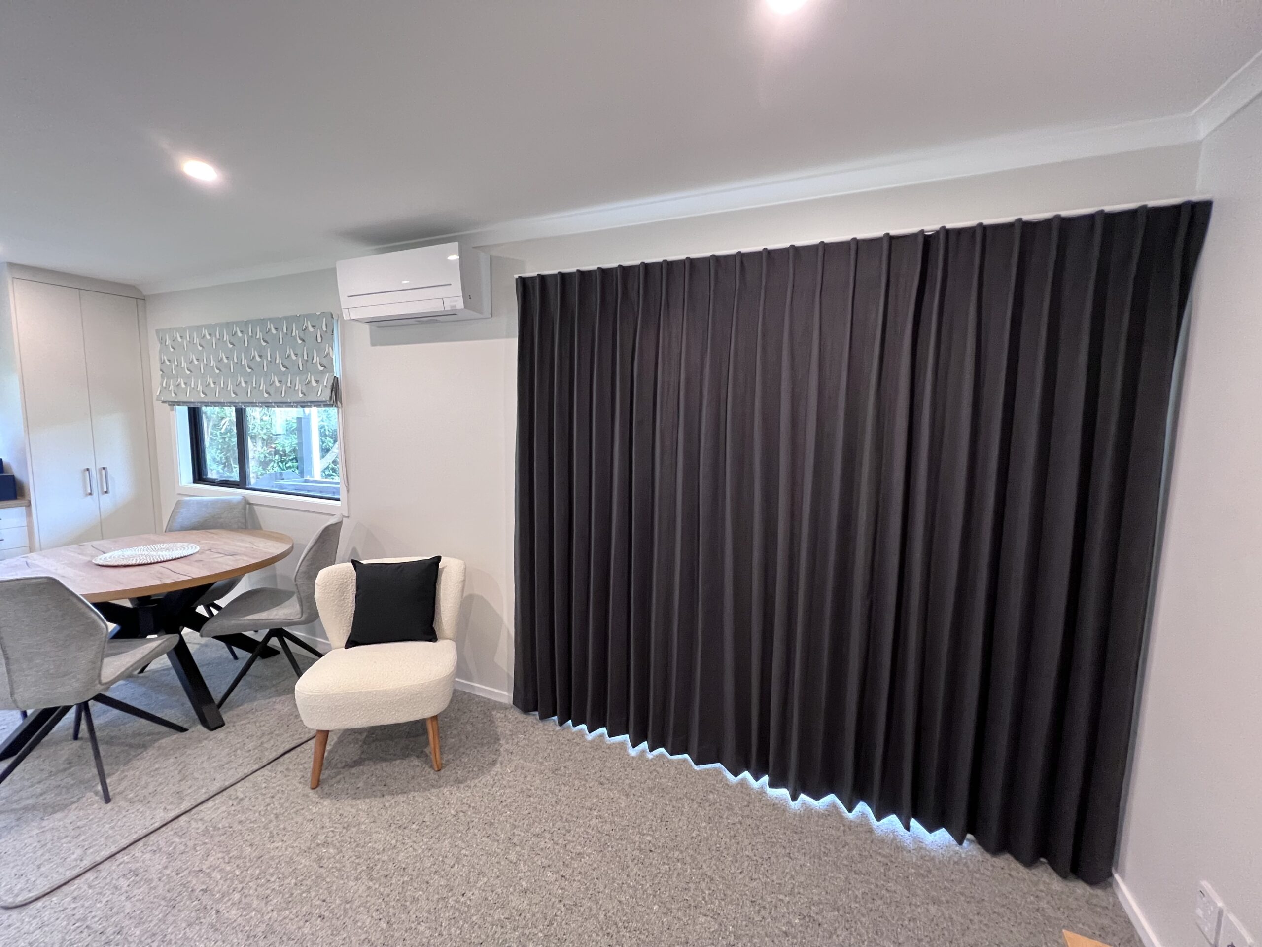 Thermal curtains Black thermal curtains in a living room against a white wall and window.